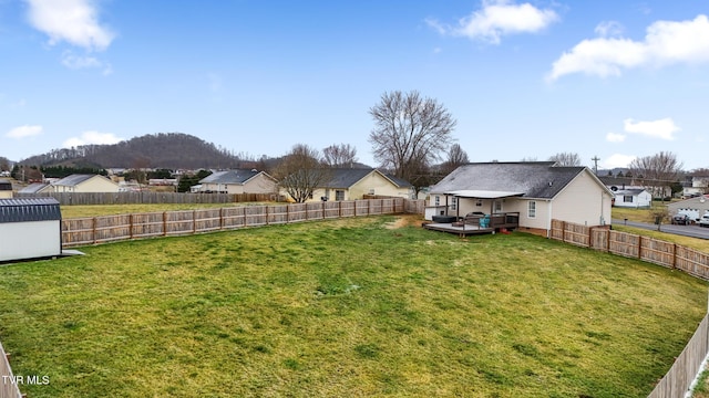 view of yard with a residential view, a fenced backyard, and a deck with mountain view