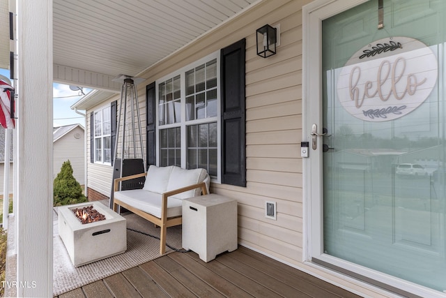 wooden deck with covered porch and a fire pit