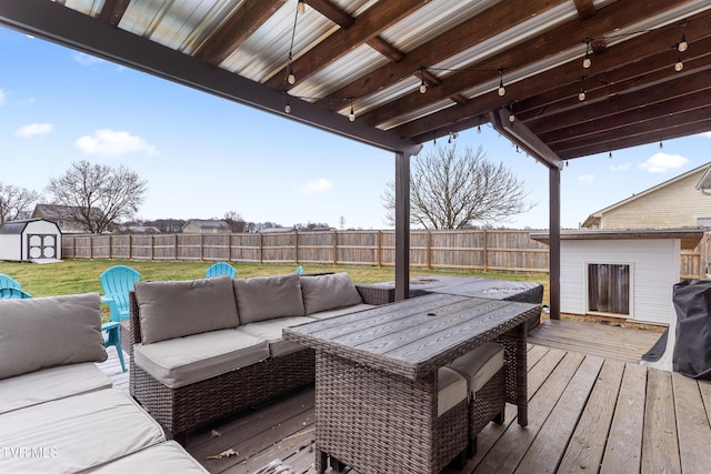 wooden deck featuring a fenced backyard, a storage unit, an outdoor living space, and an outdoor structure