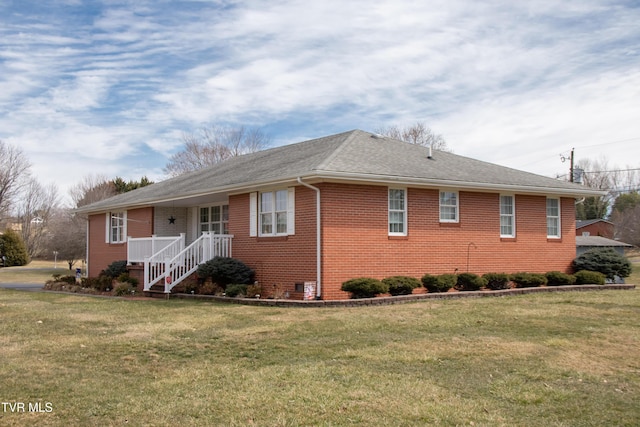 view of front of home with a front lawn, roof with shingles, and brick siding