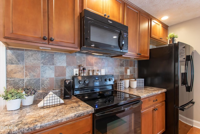 kitchen featuring light stone counters, brown cabinets, decorative backsplash, and black appliances