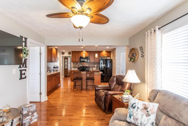 living area with light wood finished floors and a ceiling fan