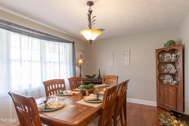 dining space featuring baseboards and dark wood-style flooring
