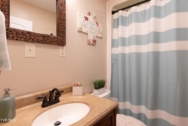 bathroom with curtained shower, vanity, and toilet