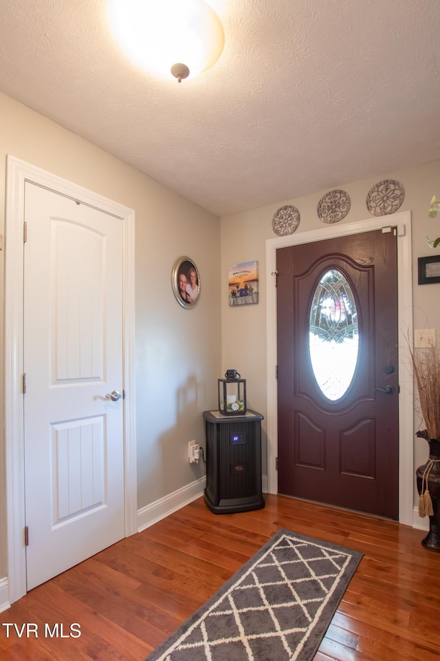 entryway with a textured ceiling, wood finished floors, and baseboards
