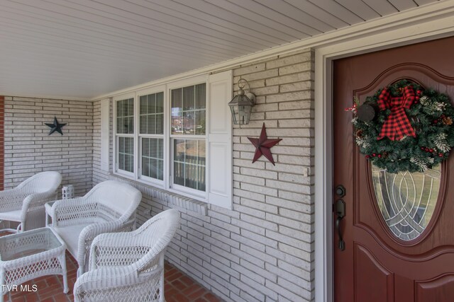 entrance to property with a porch and brick siding
