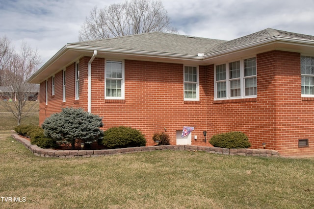 view of side of property with crawl space, brick siding, a lawn, and roof with shingles