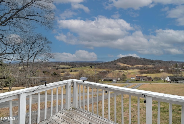 wooden terrace featuring a rural view and a mountain view