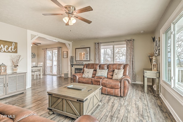 living area with a healthy amount of sunlight, light wood-style flooring, a ceiling fan, and a textured ceiling