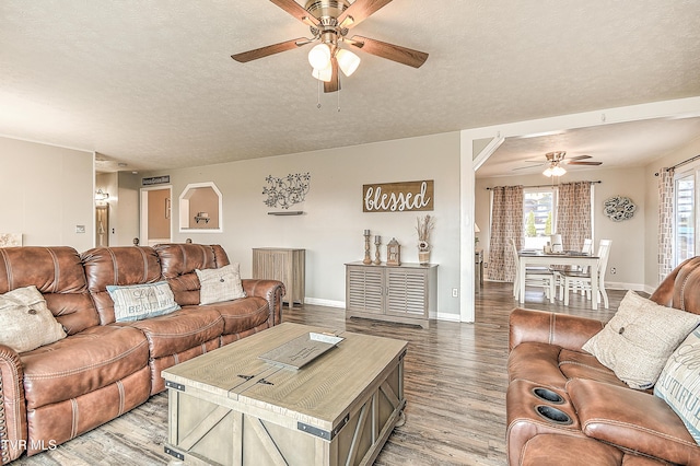 living area with a ceiling fan, baseboards, a textured ceiling, and light wood finished floors