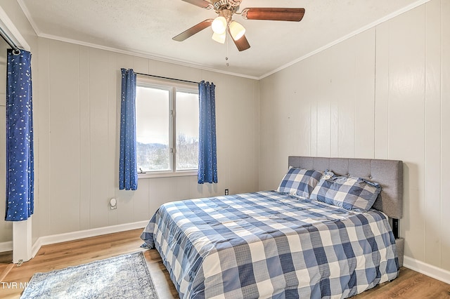 bedroom featuring a ceiling fan, crown molding, baseboards, and wood finished floors