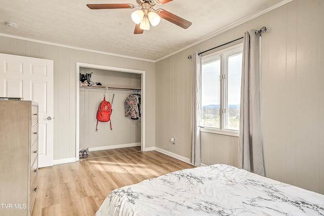 bedroom featuring baseboards, a ceiling fan, wood finished floors, crown molding, and a closet