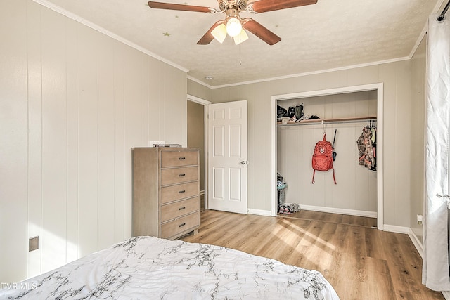 bedroom with crown molding, a closet, a ceiling fan, and wood finished floors