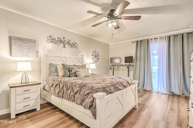 bedroom featuring a textured ceiling, ornamental molding, light wood-type flooring, and a ceiling fan