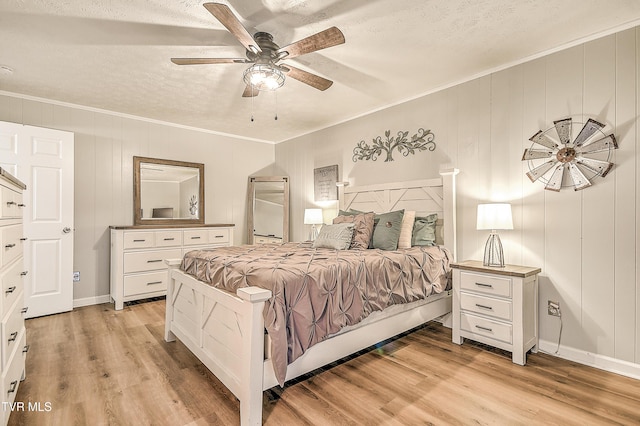 bedroom with light wood-style flooring, a textured ceiling, a ceiling fan, and crown molding