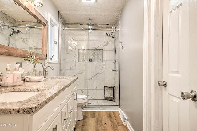 full bathroom with a textured ceiling, a stall shower, wood finished floors, and toilet