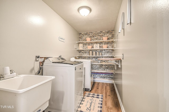 washroom featuring a sink, wood finished floors, laundry area, independent washer and dryer, and baseboards