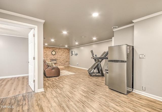 workout area with baseboards, ornamental molding, light wood-style floors, a fireplace, and recessed lighting