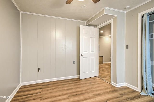 empty room featuring ornamental molding, a ceiling fan, baseboards, and wood finished floors