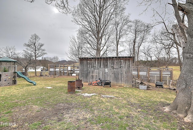 view of yard with a playground, fence, and an outdoor structure