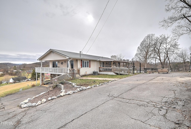 view of front of house featuring a porch, cooling unit, and driveway