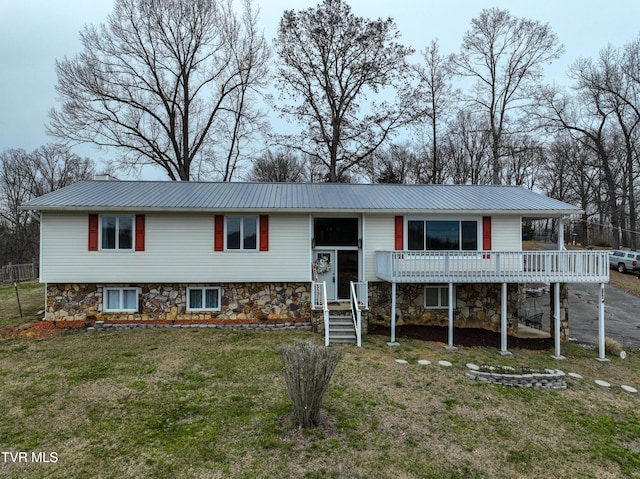 raised ranch with a front yard, metal roof, and a deck