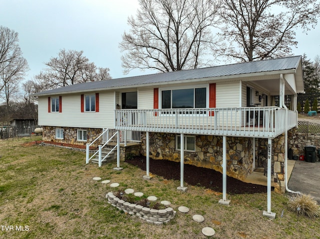 view of front of home featuring metal roof, stone siding, stairway, a wooden deck, and a front lawn