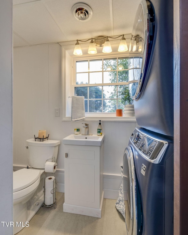 bathroom featuring stacked washer and dryer, visible vents, vanity, and toilet