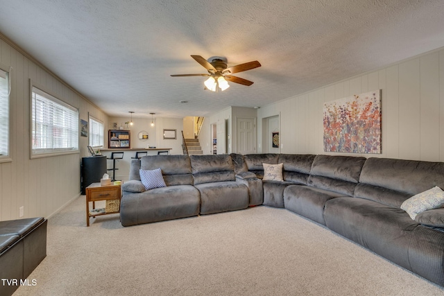 carpeted living room with stairs, a textured ceiling, and a ceiling fan