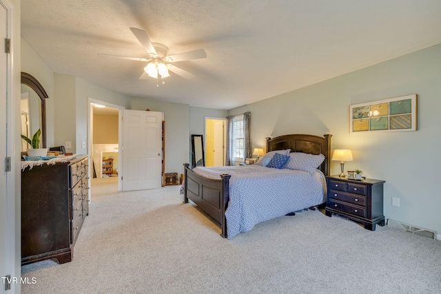 bedroom with ceiling fan, visible vents, a textured ceiling, and light colored carpet