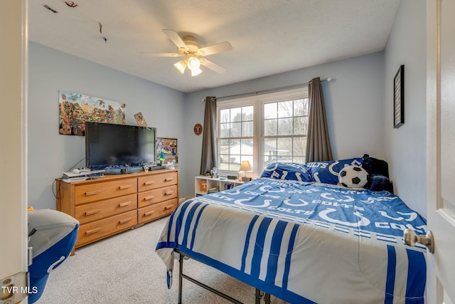 carpeted bedroom featuring ceiling fan and a textured ceiling