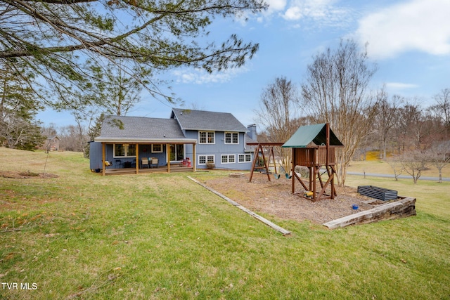 rear view of house featuring a chimney, a lawn, and a playground