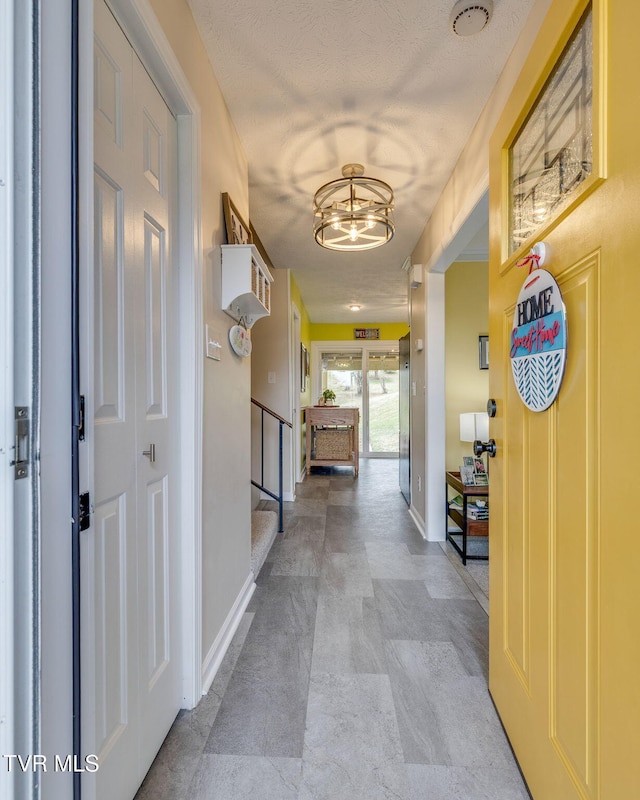 hallway with an inviting chandelier, stairway, baseboards, and a textured ceiling