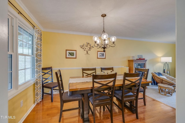 dining space with light wood finished floors, baseboards, a chandelier, and crown molding