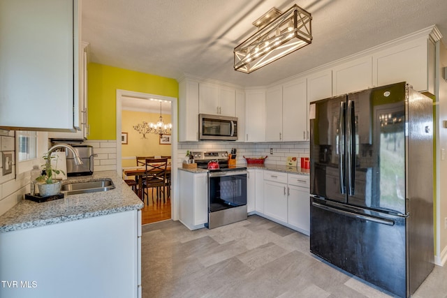 kitchen featuring decorative backsplash, white cabinets, appliances with stainless steel finishes, light stone countertops, and a sink