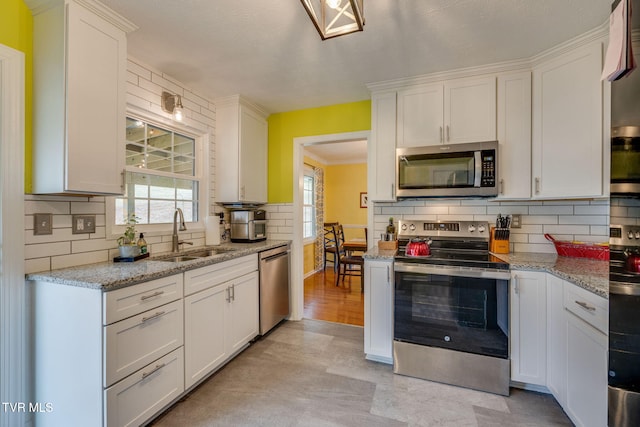 kitchen with appliances with stainless steel finishes, backsplash, a sink, and white cabinets