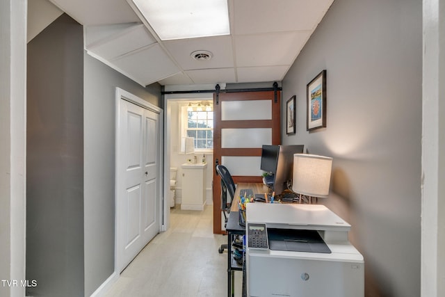 home office with a paneled ceiling, visible vents, a sink, and a barn door