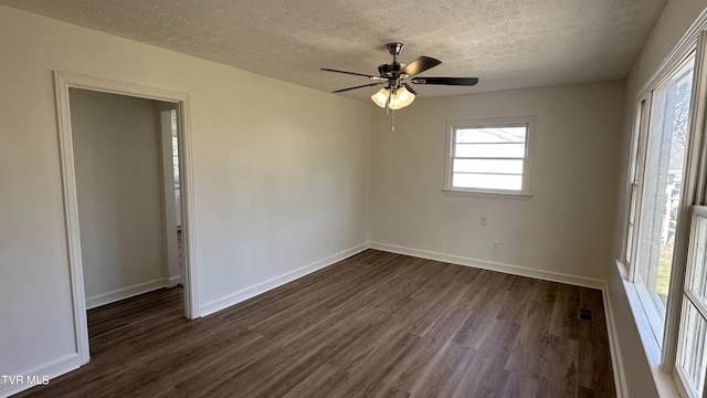 unfurnished room featuring a textured ceiling, dark wood-type flooring, visible vents, and baseboards