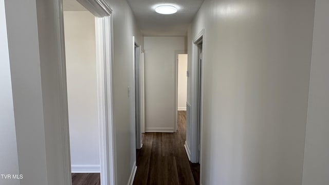 hallway featuring dark wood-style floors and baseboards