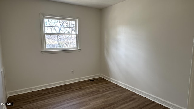 unfurnished room featuring dark wood finished floors, visible vents, and baseboards