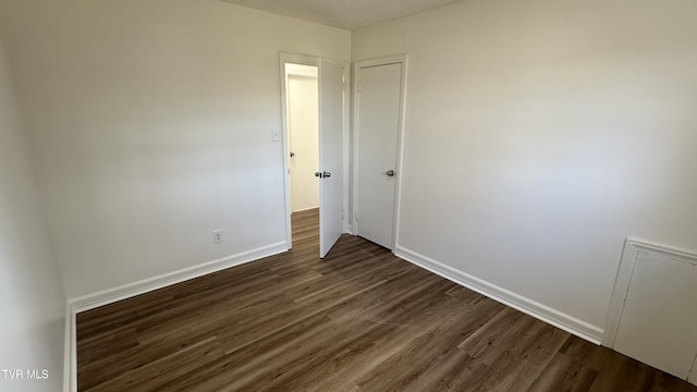 empty room with dark wood-style flooring and baseboards