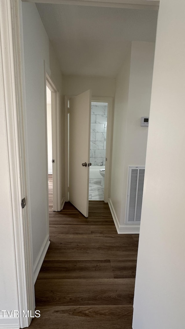 corridor with visible vents, dark wood finished floors, and baseboards