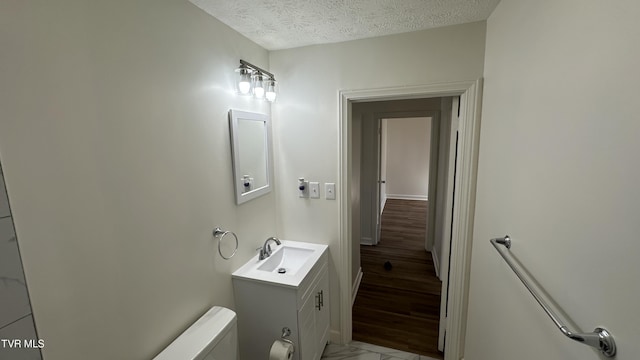 bathroom with toilet, a textured ceiling, and vanity