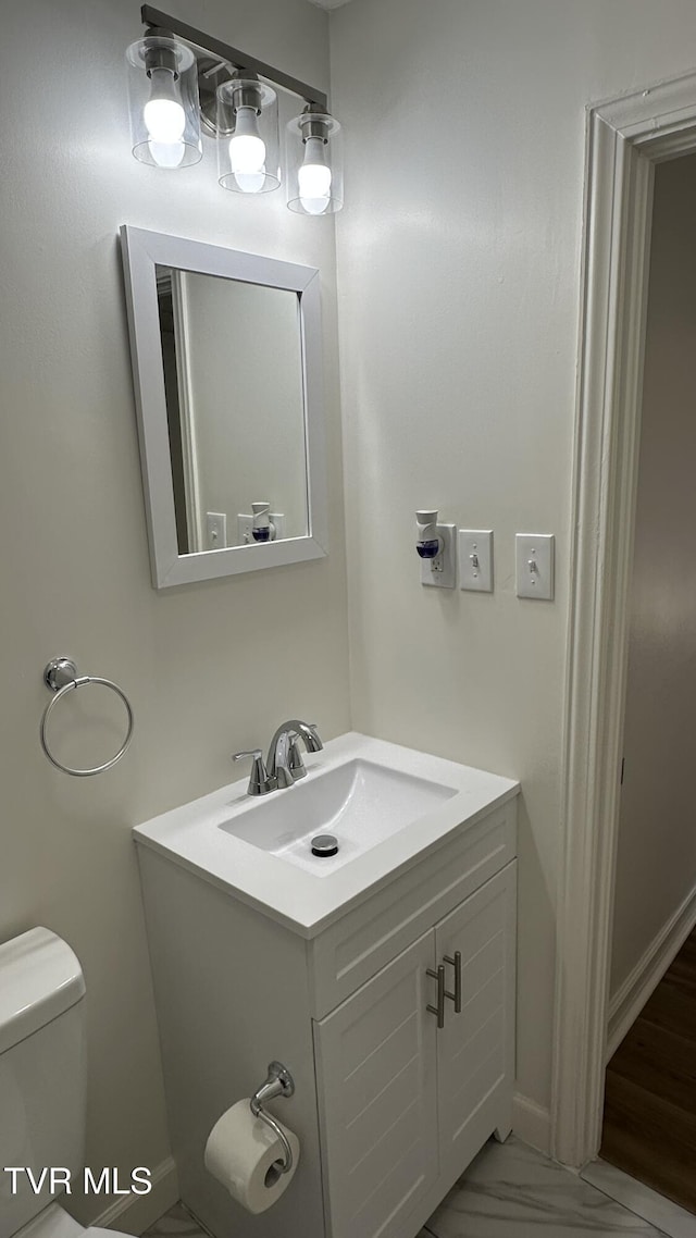 bathroom with toilet, marble finish floor, and vanity