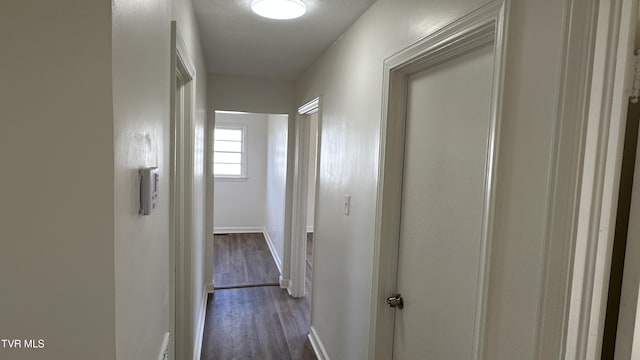 hallway with dark wood-style floors and baseboards