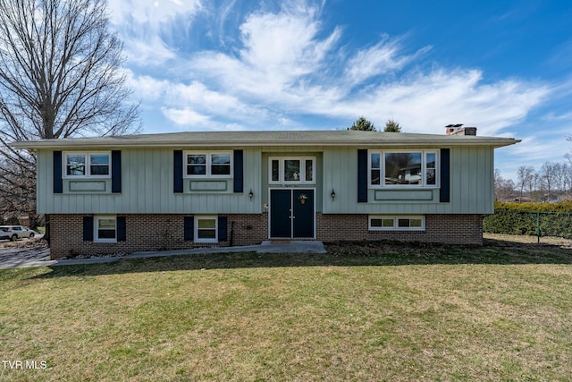 split foyer home featuring a front yard, fence, and brick siding