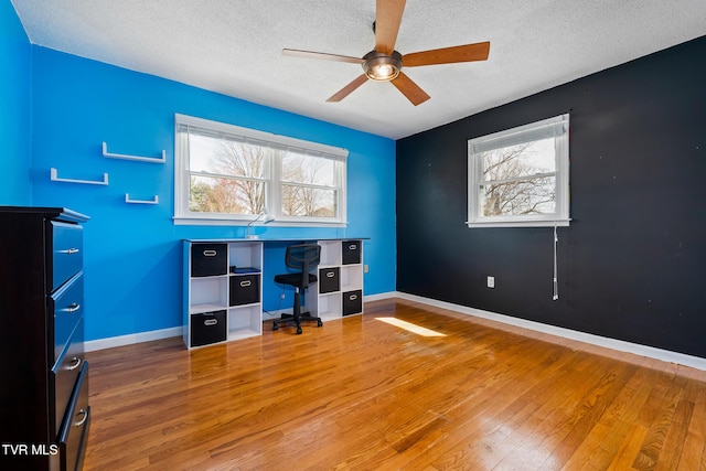 office space featuring baseboards, a textured ceiling, and light wood-style flooring