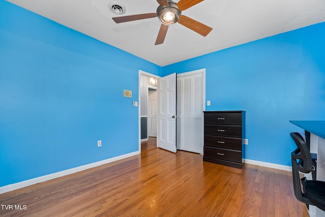 unfurnished office featuring visible vents, ceiling fan, baseboards, and wood finished floors