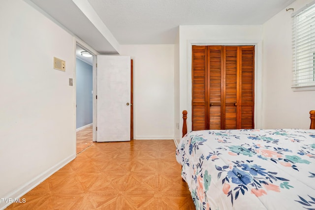 bedroom with a closet, a textured ceiling, and baseboards