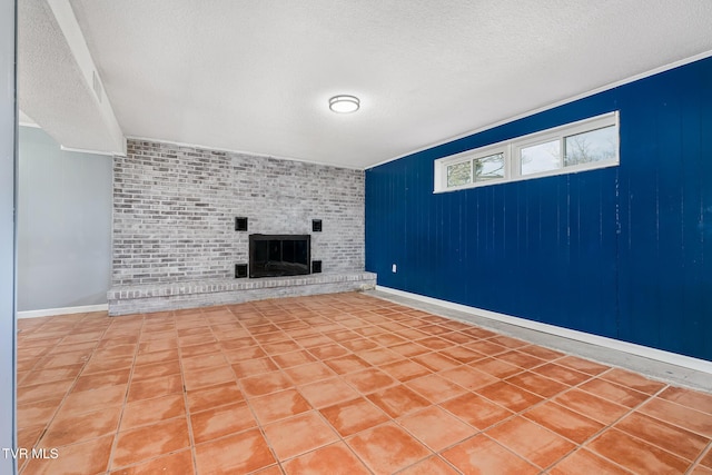 interior space with baseboards, a textured ceiling, a brick fireplace, and tile patterned flooring